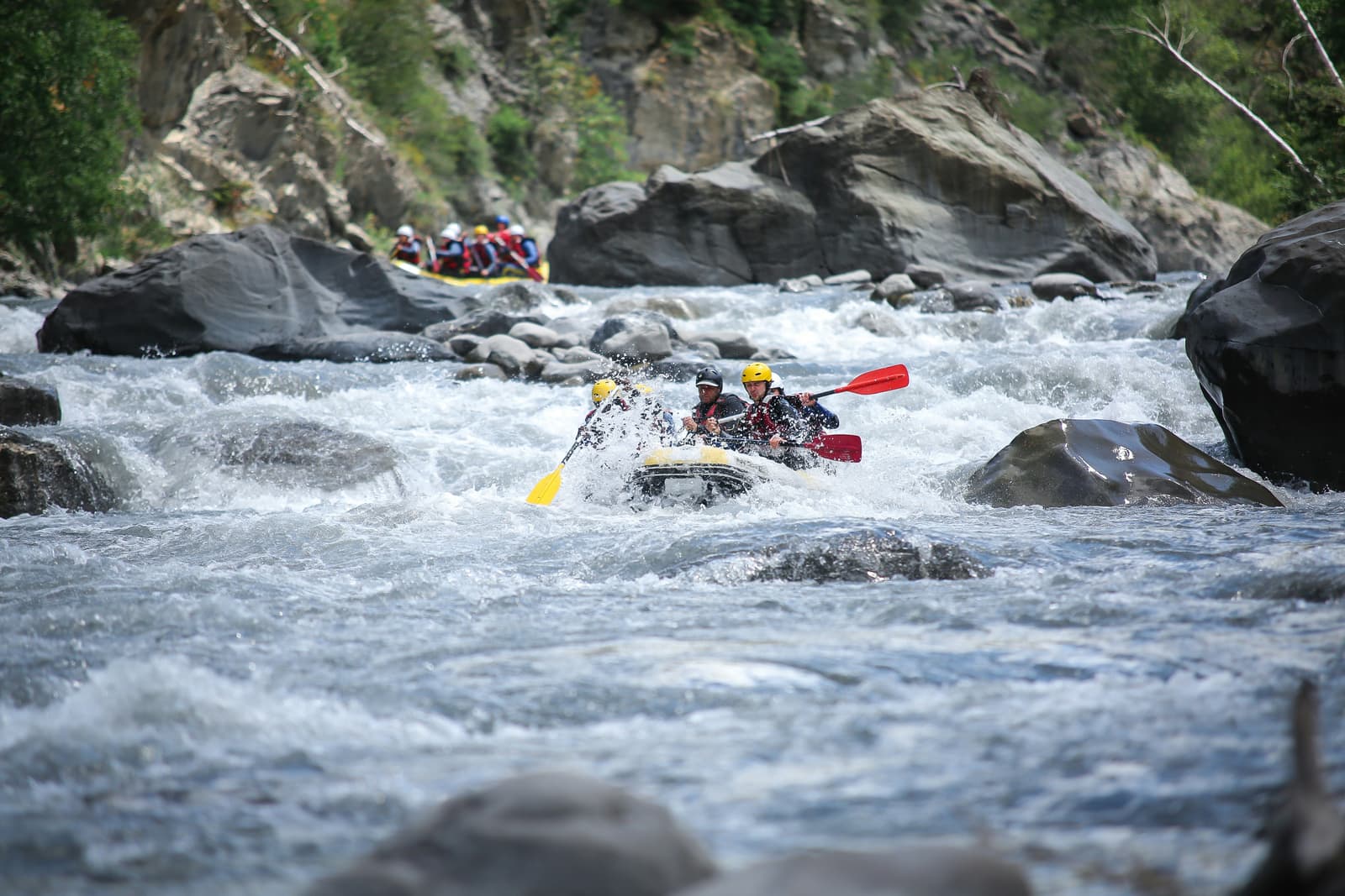 Travellers white-water rafting through rocky river rapids