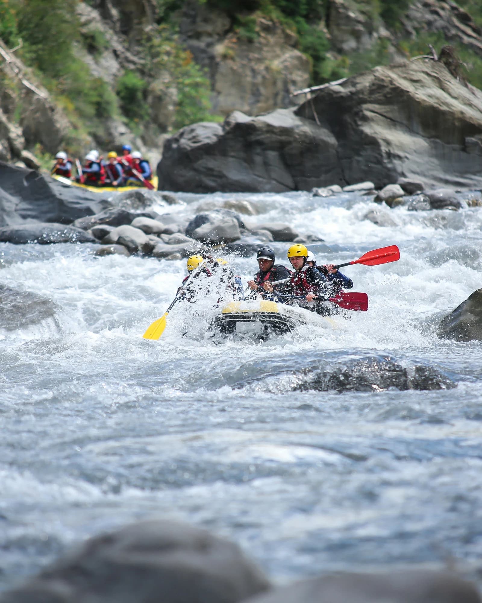 Travellers white-water rafting through rocky river rapids